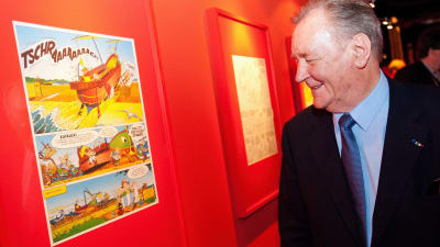 Asterix -sarjakuvan piirtäjä ja käsikirjoittaja Albert Uderzo katselee sarjakuvasivua, joka on seinällä