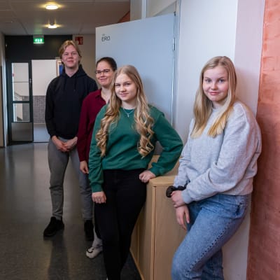 Miro Kuntsi, Henna Ijäs, Noora Torkki ja Tinja Louho Petäjäveden lukion käytävällä. He kaikki katsovat kameraan ja hymyilevät.