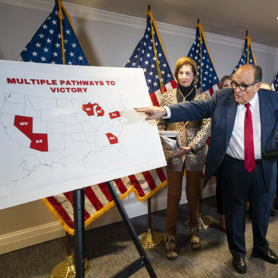 Man i kostym pekar på karta över USA. Mannen är Trumps advokat Rudy Giuliani.