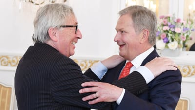 Jean-Claude Juncker och Sauli Niinistö ler glatt medan de omfamnar varandra.