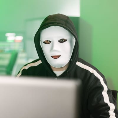 Maskerad hackare arbetar vid en laptop. 