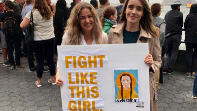 Caoimhe Craven och Sarah Kelly i New Yorkhåller ett plakat med texten "Fight like this girl" och en tecknad bild på Greta Thunberg.