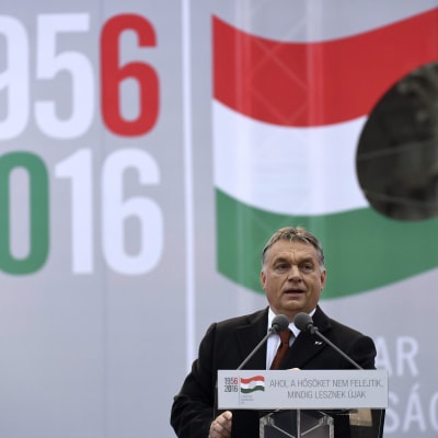 Viktor Orban med den ungerska flaggan och årtalen 1956 och 2016 i bakgrunden. Orban talar på en minnesceremoni för Ungernrevolten 1956