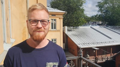Blond man med glasögon står i solen. 
