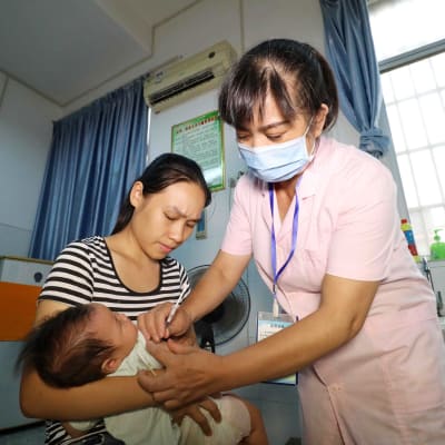 Sjukskötare vaccinerar spädbarn i Kina. 