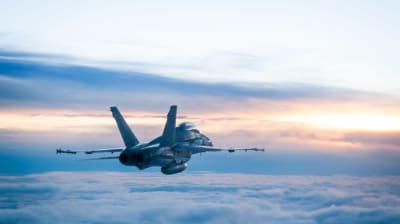 Ett Hornet-jaktplan från finska flottan flyger ovan molnen.