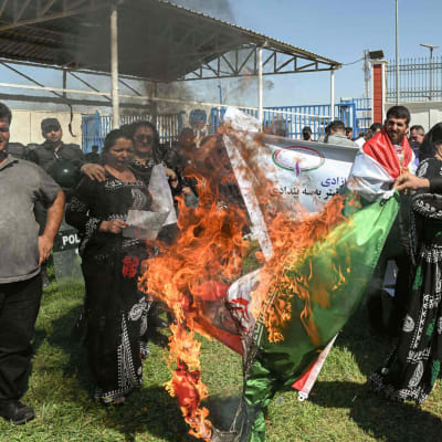 Människor bränner en iransk nationalflagga under en demonstration.