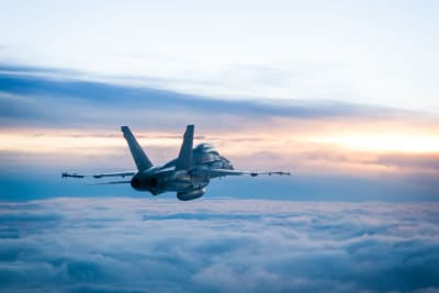 Ett Hornet-jaktplan från finska flottan flyger ovan molnen.