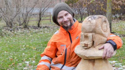 Niko Nordström ler och har armen runt en skulptur av en snigel som sitter på en sopp.