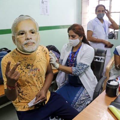 Terveydenhoitaja antaa koronarokotteen intialaiselle henkilölle.
