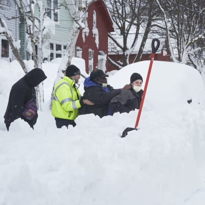 Räddningsarbetare skottar snö på en snötäckt gata.