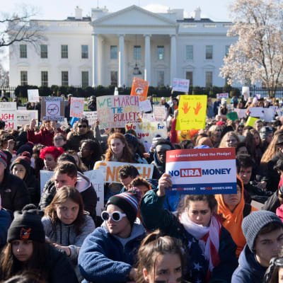 Hundratals elever med protestplakat sitter utanför Vita huset.