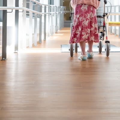 Vanhus kävelee rollaattorin kanssa kaltevaa käytävää Myyrmäen vanhustenkeskuksessa, Vantaalla.