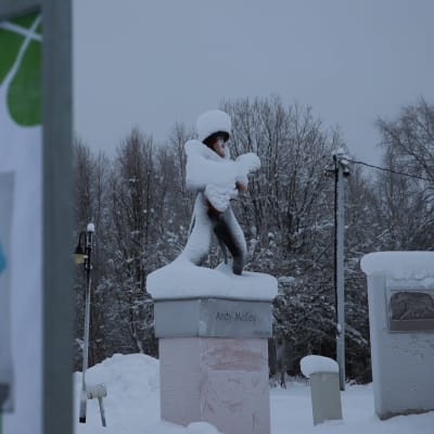 vaalimainos ja lumenpeittämä Andy Mc Coyn patsas Pelkosenniemellä