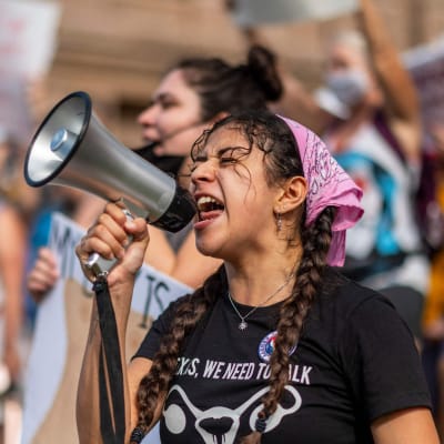 Kvinna ropar i megafon och bakom henne finns andra kvinnor som deltog i en marsch den 2 oktober 2021 mot abortlagen i Texas.