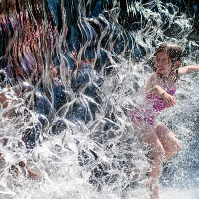 En flicka i en fontän under värmeböljan i nordamerika. 
