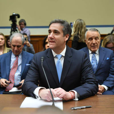 En sällsynt bild av en leende Michael Cohen under utskottsförhöret, med jurister och publik i bakgrunden