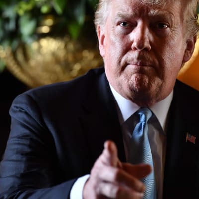Donald Trump i Mar a Lago framför en jättebukett vita blommor i vas.