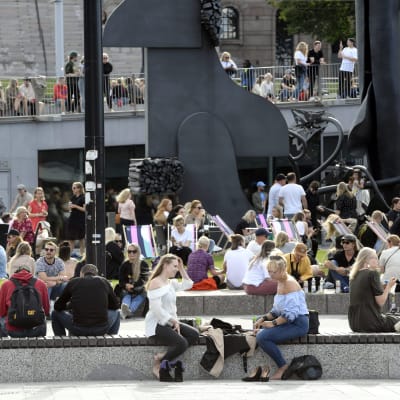 Ihmiset nauttivat kauniista kesäpäivästä Musiikkitalon edustalla Helsingissä