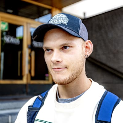 Närbild på en man med skärmössa, han står utanför Novias byggnad.  