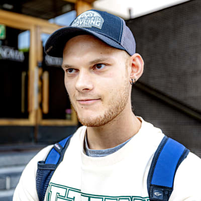Närbild på en man med skärmössa, han står utanför Novias byggnad.  