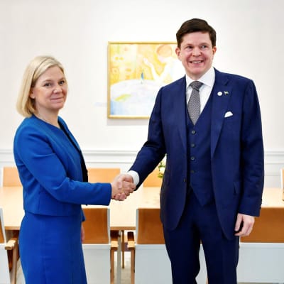 En kostymklädd kvinna och en kostymklädd man skakar hand