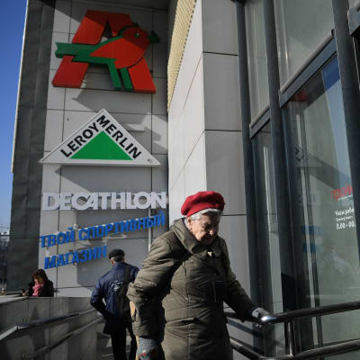 Iäkäs nainen kävelemässä sisään kauppakeskukseen Moskovassa.