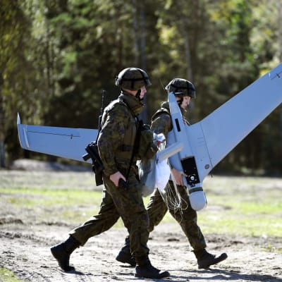 Suomen puolustusvoimien sotilaat kantava droonia. 