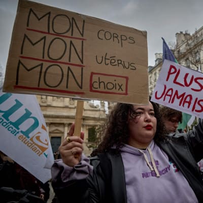 Demonstranter håller upp plakat med texten "Min kropp, min livmoder, mitt val" i Paris 28.2.2024.