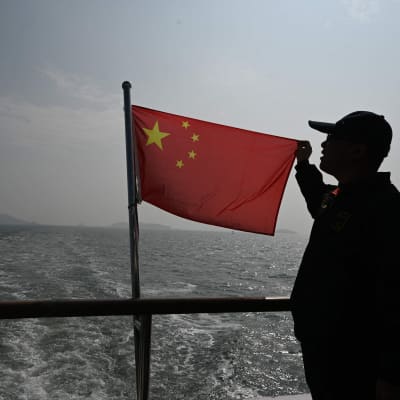 Kinas flagga och en man ombord på en båt.