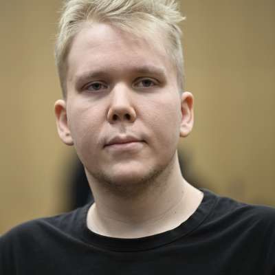 Närbild av Aleksanteri Kivimäki i en svart t-tröja som sitter i en rättssal.