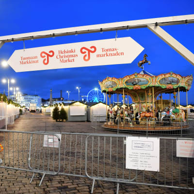 Tuomaan Markkinoiden kyltti, myyntikojuja ja karuselli Helsingin Kauppatorilla.