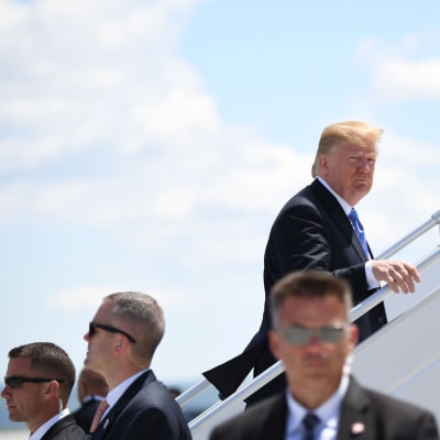 Donald Trump omgiven av livvakter går upp för trappan till sitt flygplan