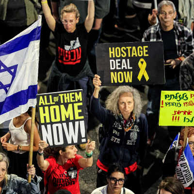 Människor bär plakat och flaggor i Israel i en demonstration för att gisslan ska bli frisläppta.
