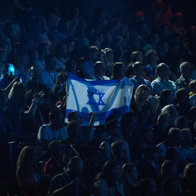 Yleisön keskellä joku pitää ylhäällä Israelin lippua.
