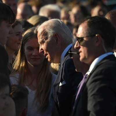 Presidentti Biden puhuu nuorten ihmisten kanssa jotka ovat tulleet katsomaan hänen saapumistaan Vilnan lentokentälle.