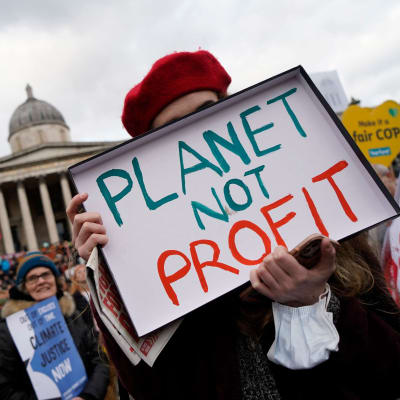 En person bär en skylt med texten "Planet not profit" (planeten, inte vinsten) på Trafalgar Square i London under en demonstration den 6 november 2021.