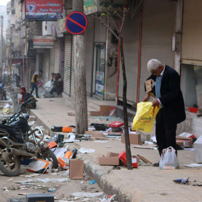 En man utanför en butik som utsatts för plundring i Afrin.