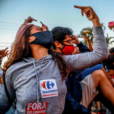Demonstration i Porto Alegre 20.11.2020. En kvinna i munskydd håller upp sitt mittfinger.