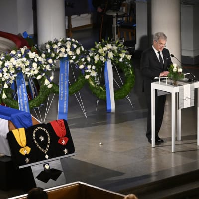 Republikens president Sauli Niinistö vid ett talarpodium i Helsingfors domkyrka. I förgrunden president Ahtisaaris kista med utmärkelsetecken.