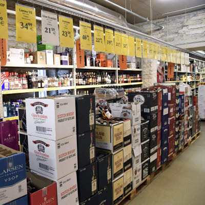 Bild från en alkoholbutik. På marken står lådor med vin och hyllorna i bakgrunden är fyllda med sprit.