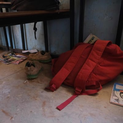 Punainen reppu ja kenkiä lattialla. Tavarat kuuluivat koulusta siepatuille lapsille.