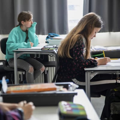 Tre danska elever sitter vid sina pulpeter. 