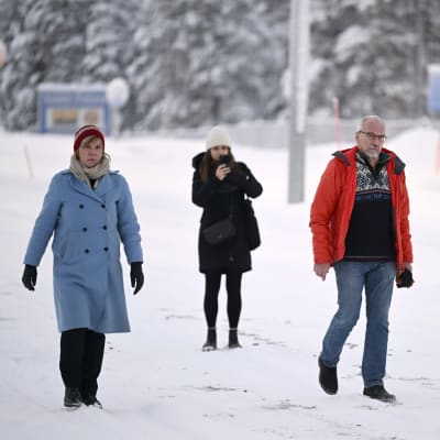 Anna-Maja Henriksson och Nils Torvalds går i snön vid gränsen Raja-Jooseppi. En fotograf syns i bakgrunden.