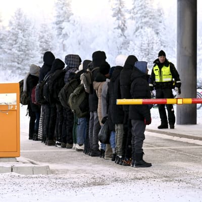 Turvapaikanhakijat ovat rivissä Suomen tullivirkailijan edessä kansainvälisellä rajanylityspaikalla Sallassa.