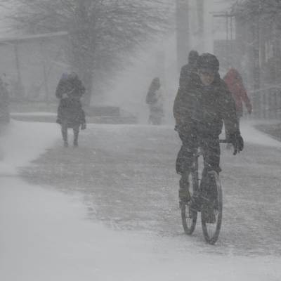 En cyklist i Helsingfors.  Snön yr, men marken är delvis bar.