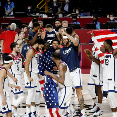 Glädjehög med amerikanska basketspelare i vita speltröjor och med flaggor.