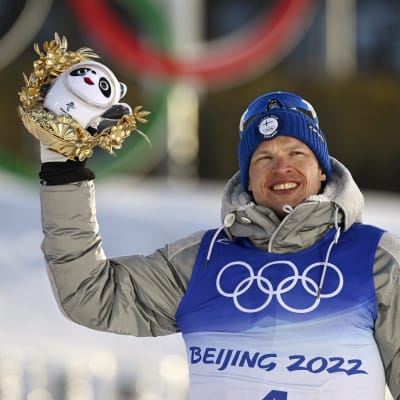 Iivo Niskanen håller i en slags pokal i brons under OS i Peking. Han ler.