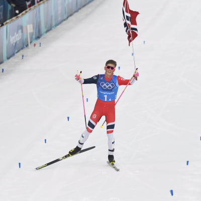 Kläbo med den norska flaggan i handen då han korsar mållinjen