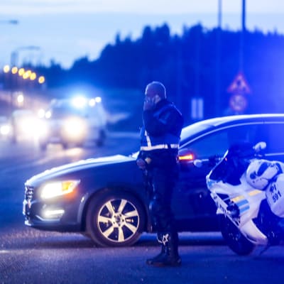 En polis står bredvid en polisbil och en polismotorcykel